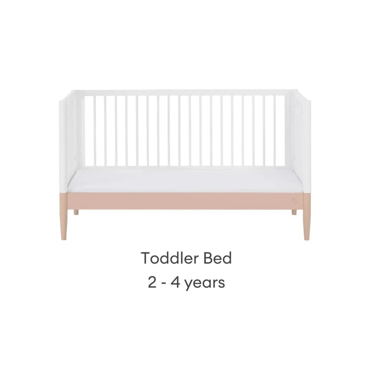 White toddler bed with powder blush rail and vertical slat headboard