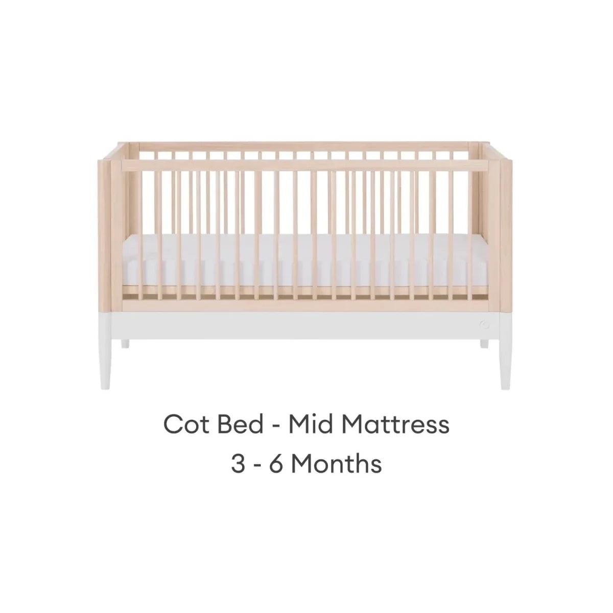 White and natural ash cot bed with mid mattress position and vertical slat guardrails