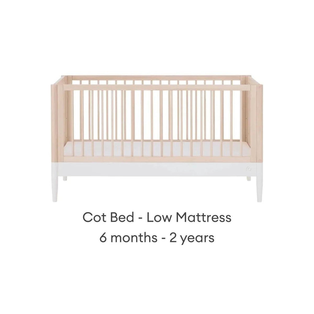 White and natural ash cot bed with low mattress position and vertical slat guardrails