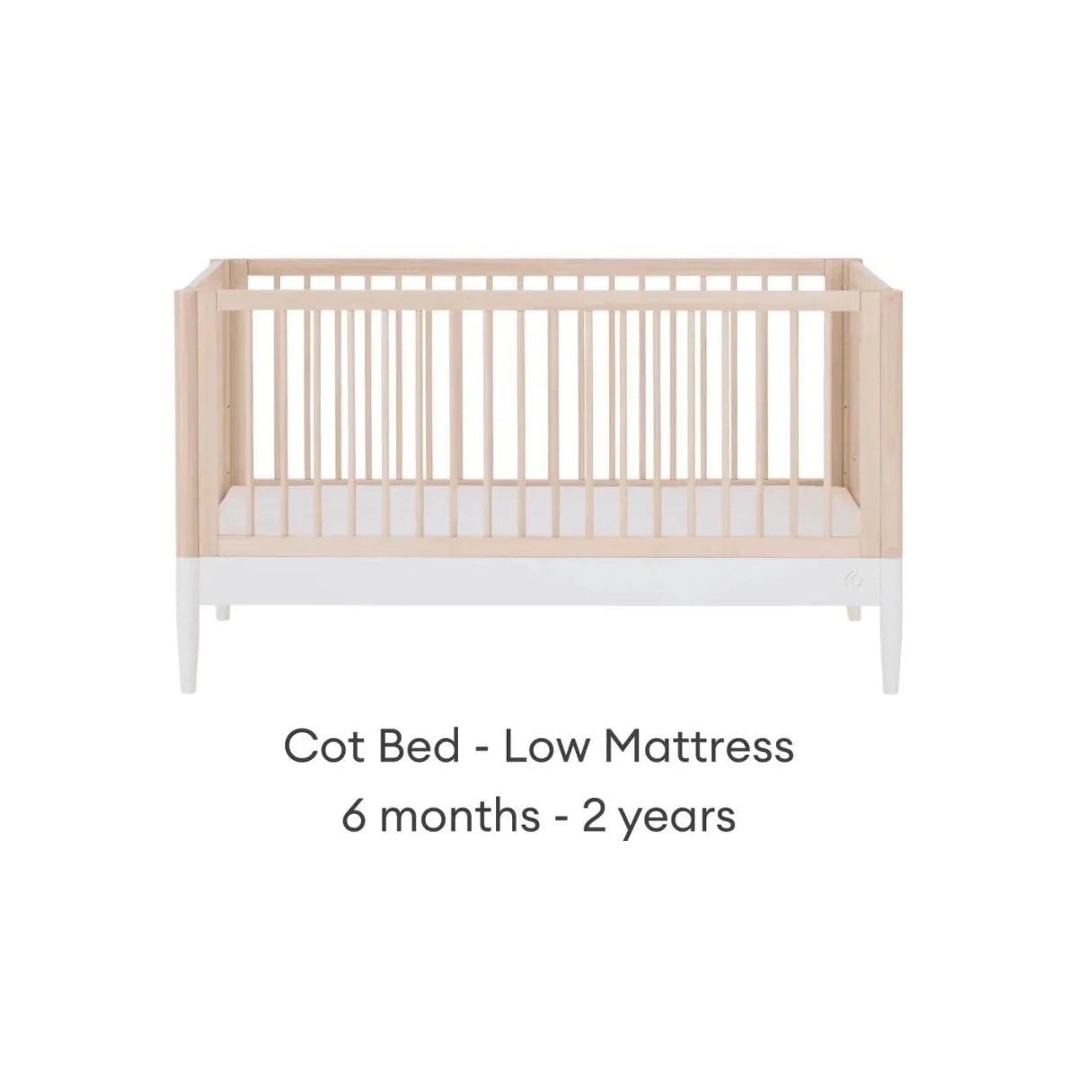 White and natural ash cot bed with low mattress position and vertical slat guardrails