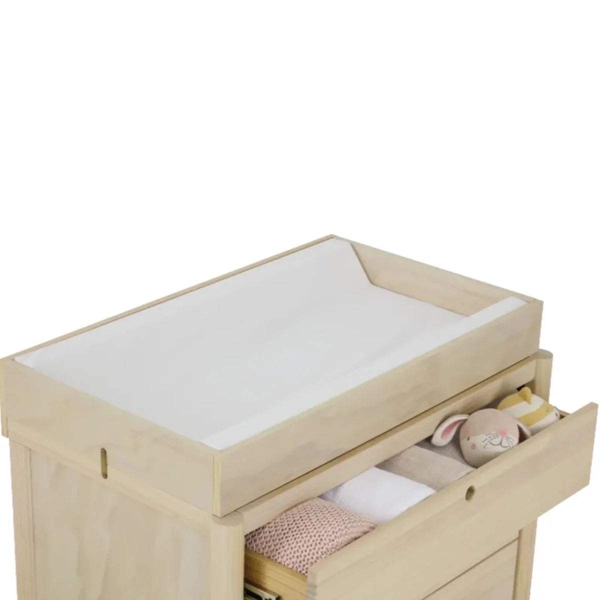 Baby changing pad on light wood dresser with open drawer compartments