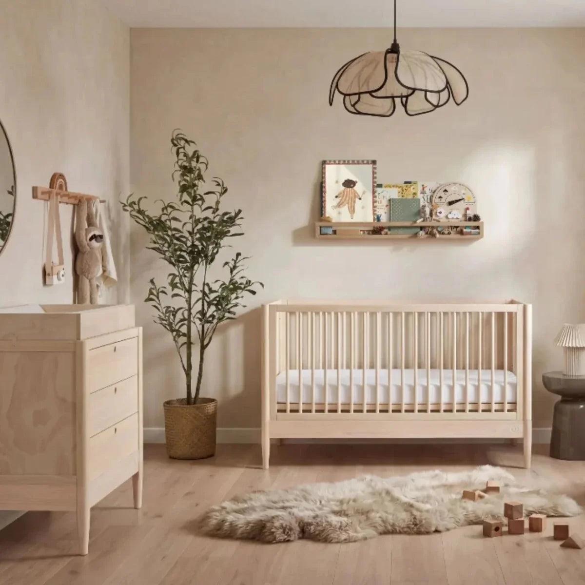 Light ash wood baby dresser with one visible drawer and round knob, flat top