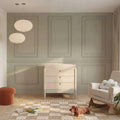 Baby dresser with three light-wood drawers and round dark knobs, on tapered legs