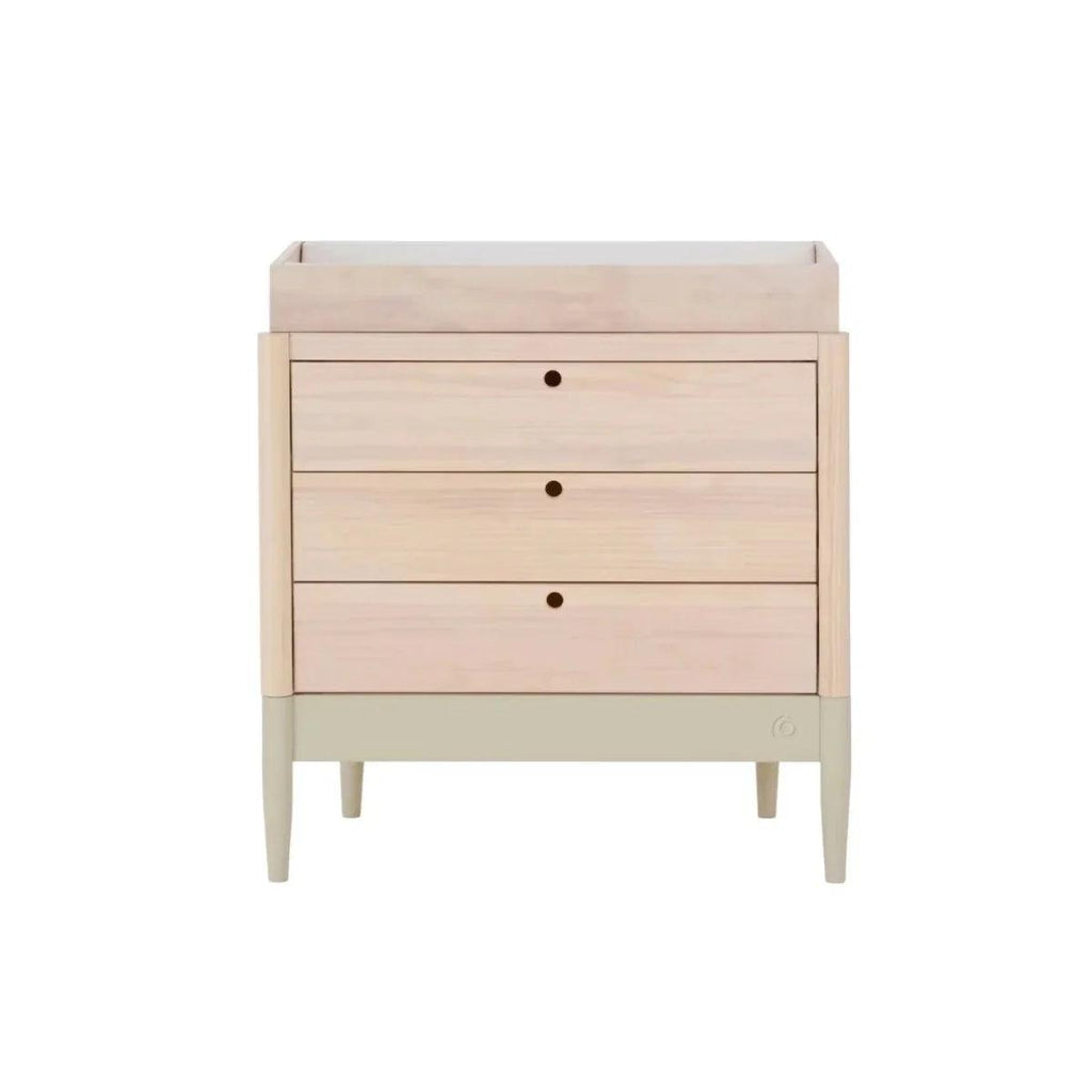 Light-wood baby dresser with three drawers, round dark knobs, and slim tapered legs