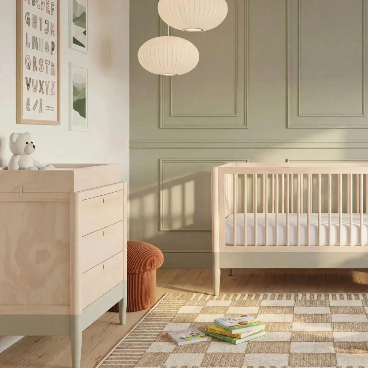 Baby dresser with three drawers and round knobs, shown in a nursery setting