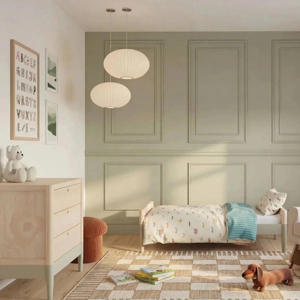 Baby dresser with three drawers and round knobs beside a crib, in a nursery