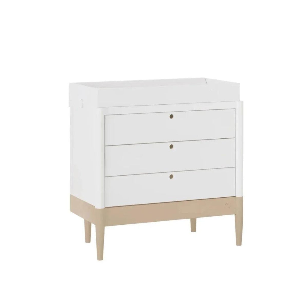 White baby dresser with three drawers, round brass-tone pulls, and tapered legs