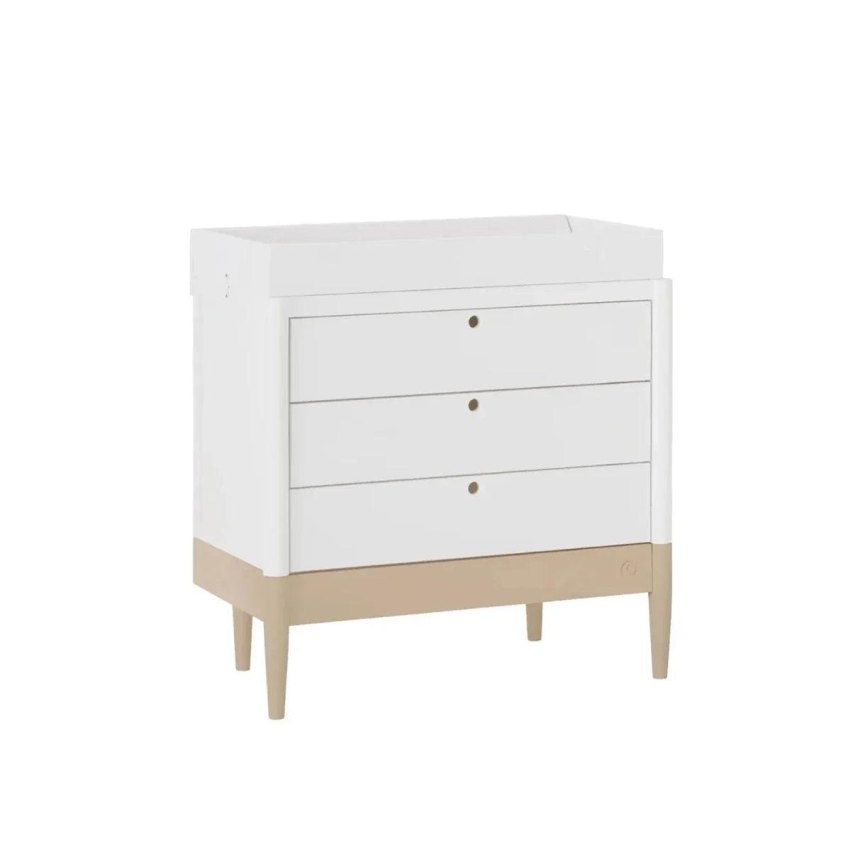 White baby dresser with three drawers, round brass-tone pulls, and tapered legs