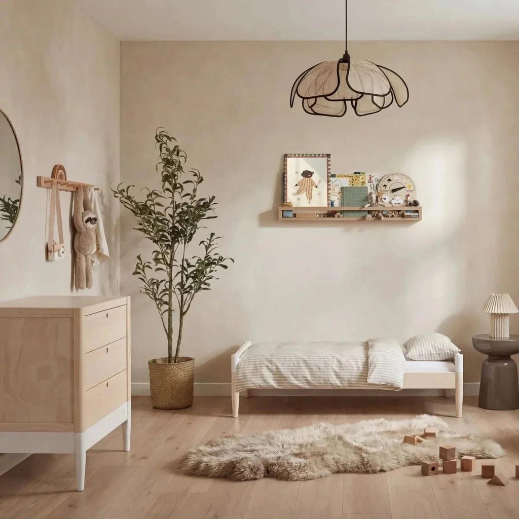 White and natural baby dresser with three drawers and round knobs in nursery setting