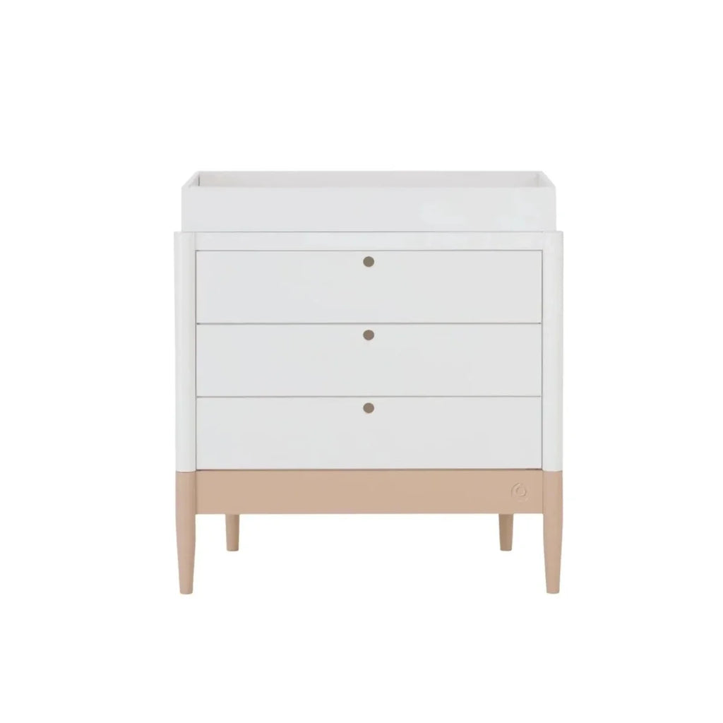 White baby dresser with three drawers and gold knobs, powder blush skirt, flat top