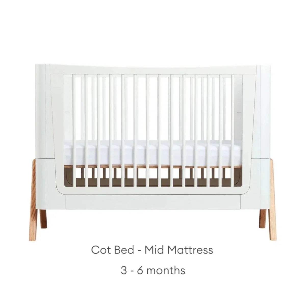 White cot bed frame with vertical slats and natural wood legs, mid platform height