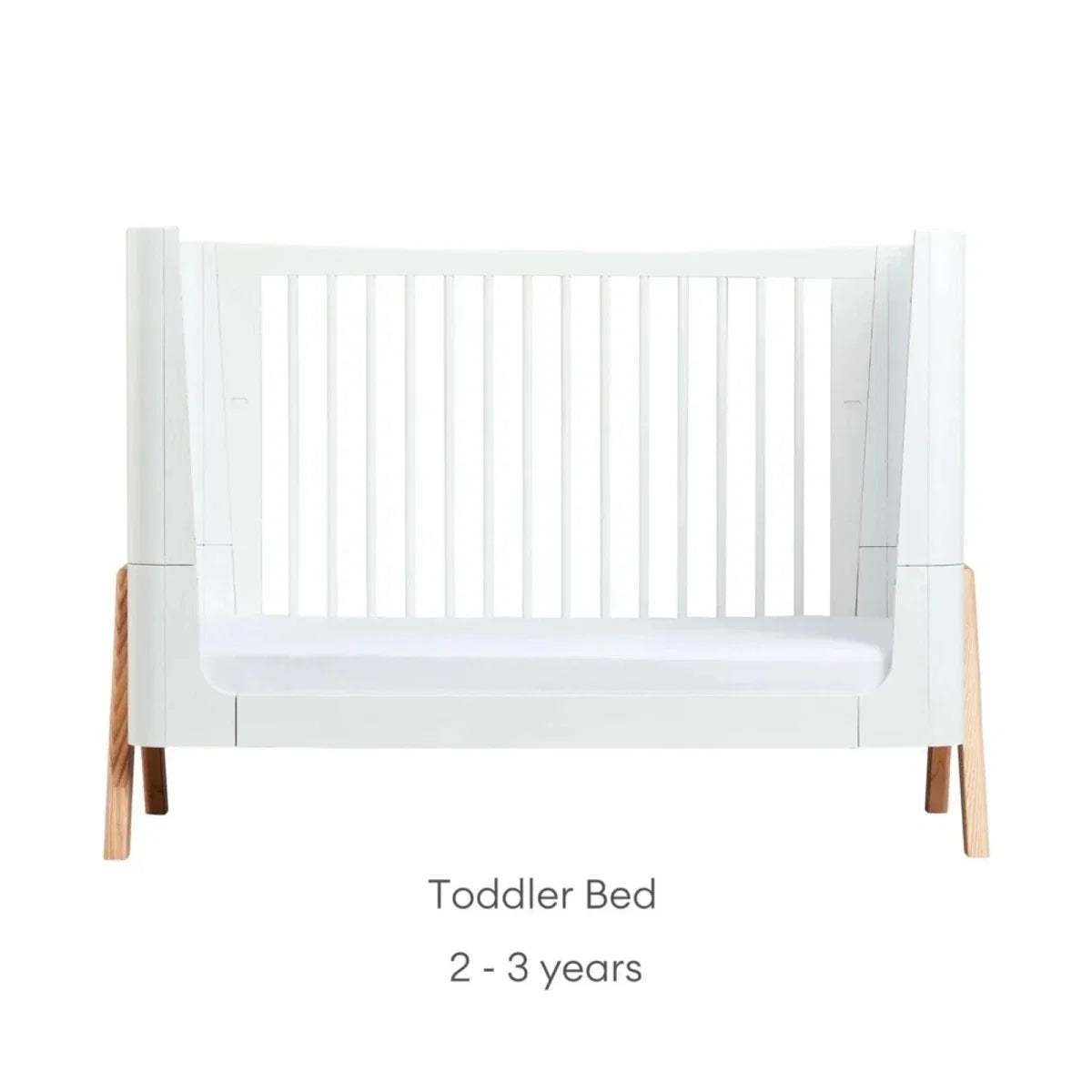 White toddler bed frame with low panel base and vertical side posts, natural wood legs
