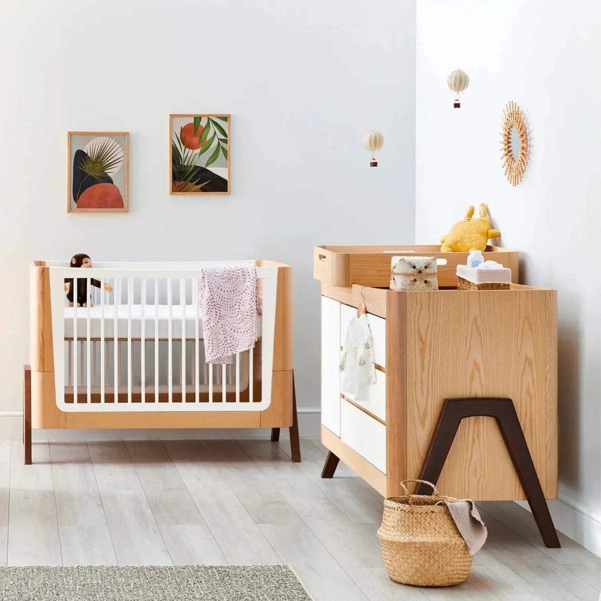 Natural wooden baby crib with vertical slats; matching baby dresser in walnut accents