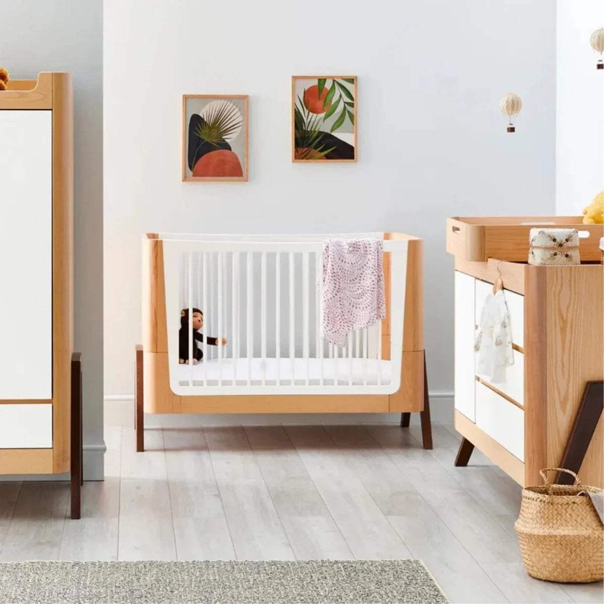 Natural wood baby crib and matching dresser set with white slats and walnut accents
