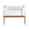 White and natural bedside crib with open side panels and mesh window