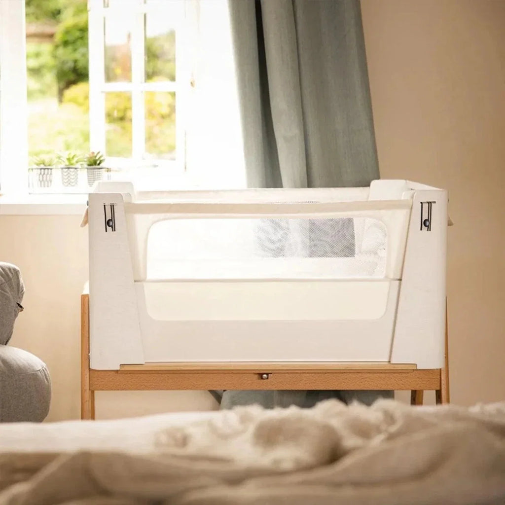 White and natural bedside crib front view with mesh side panel