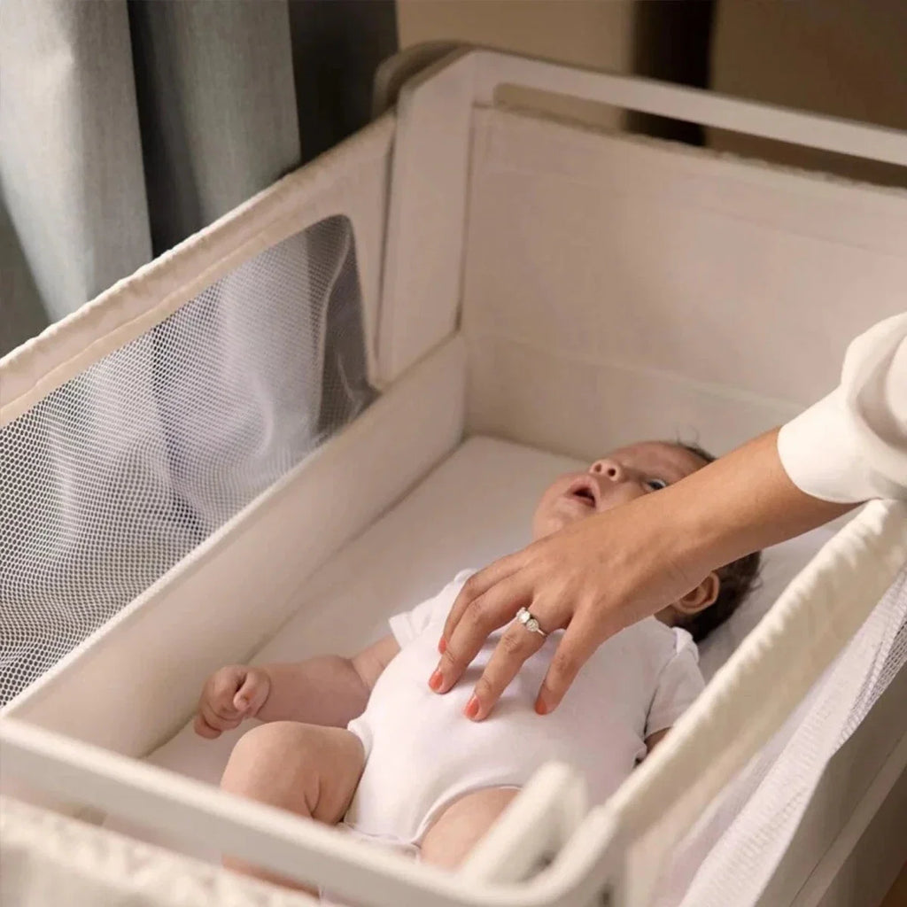 White and natural baby bedside crib with open mesh side and padded base liner