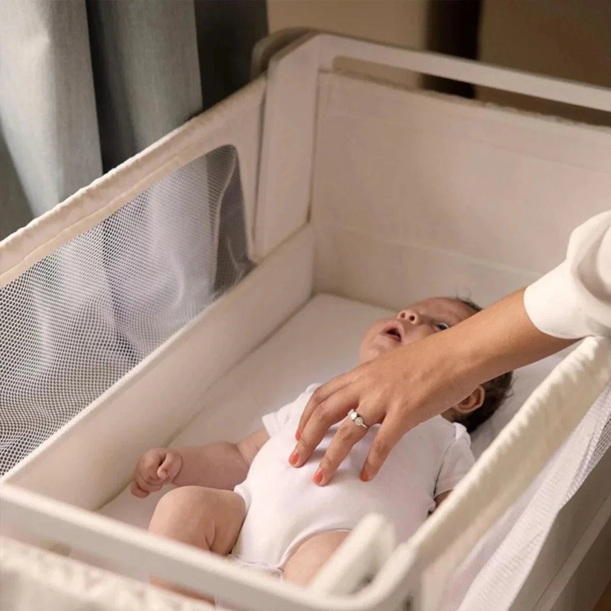 White and natural baby bedside crib with open mesh side and padded base liner