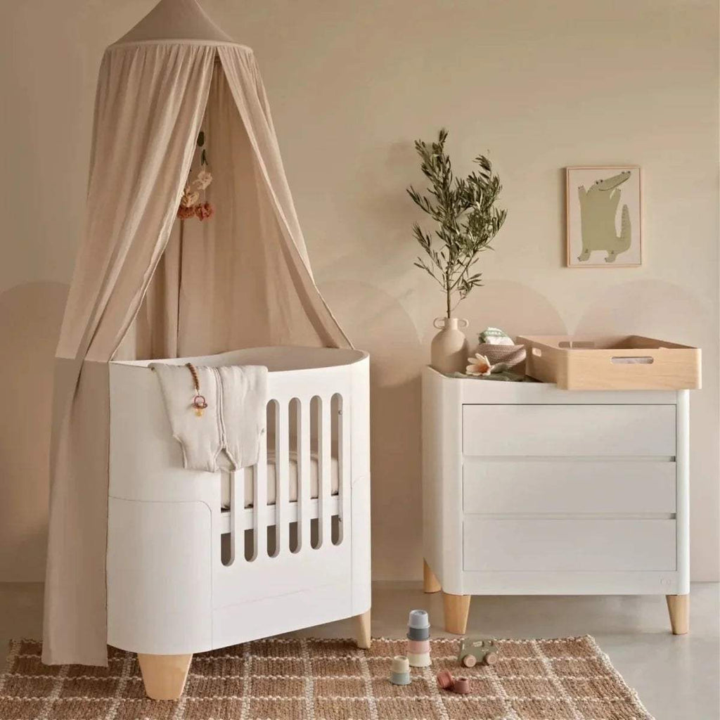 Natural wood baby changing station with white storage cabinet and top ledge