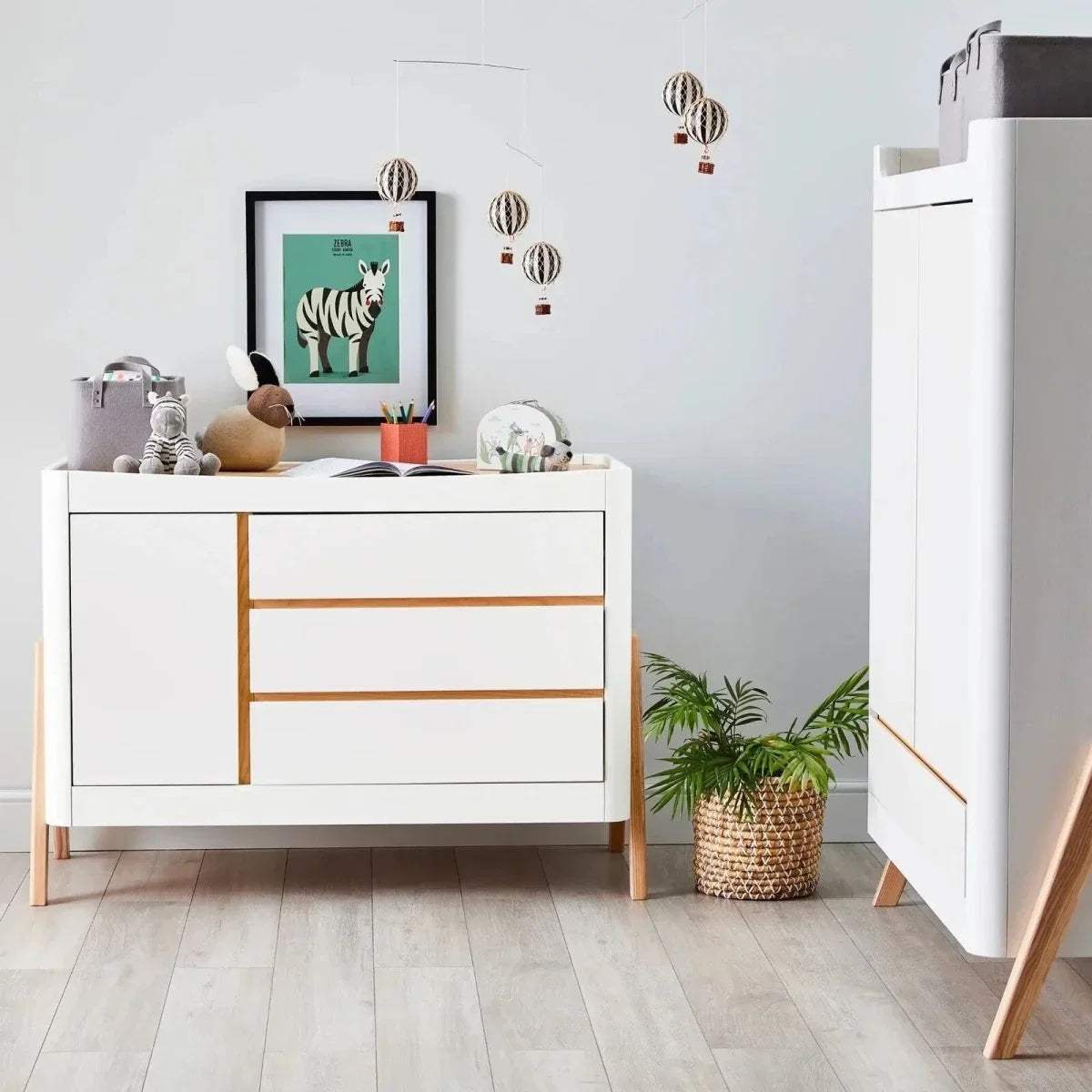Scandi baby dresser in white with natural wood trim and wide drawer center panel.