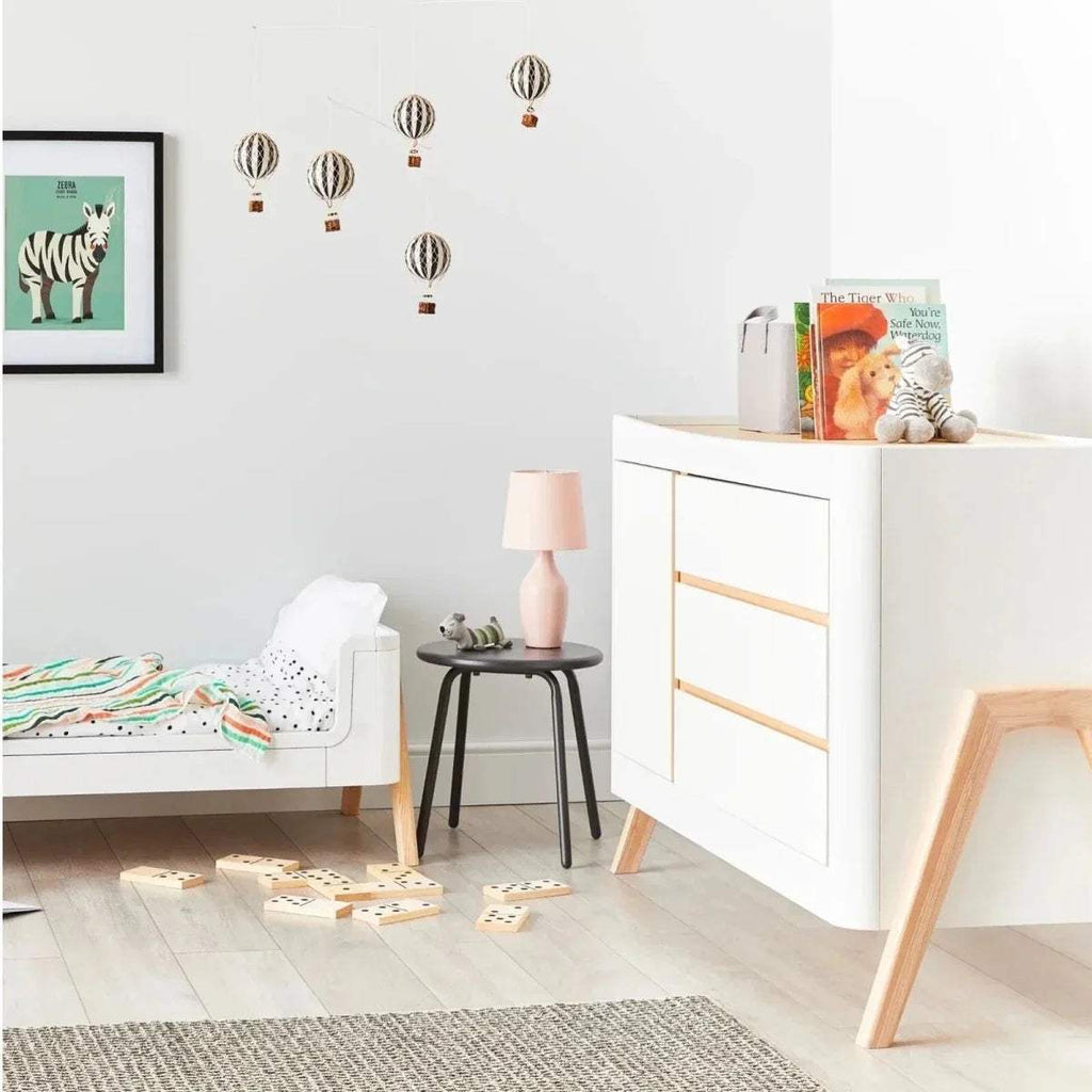 White baby dresser featuring natural wood trim and two front drawers on light legs.