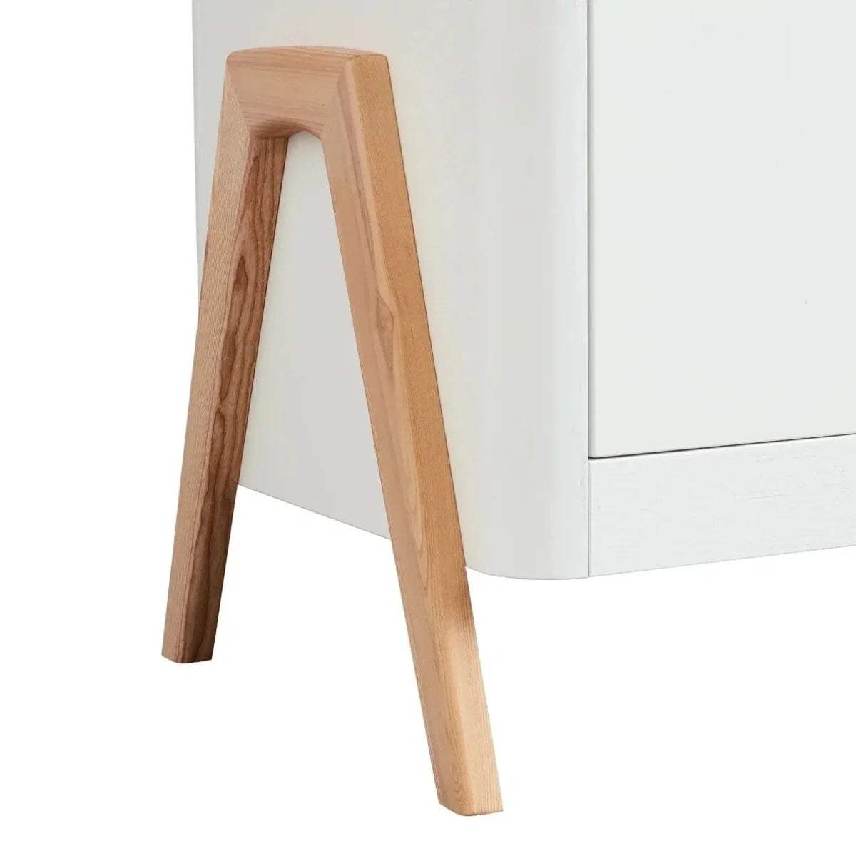 Natural wood dresser leg with tapered profile beneath a white cabinet body.