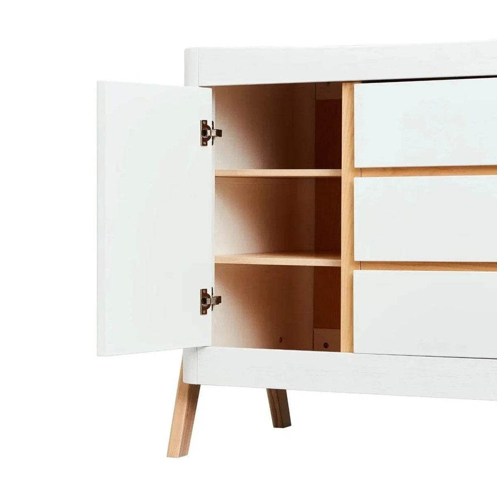 Baby dresser with left door open, showing interior shelves and natural wood frame.