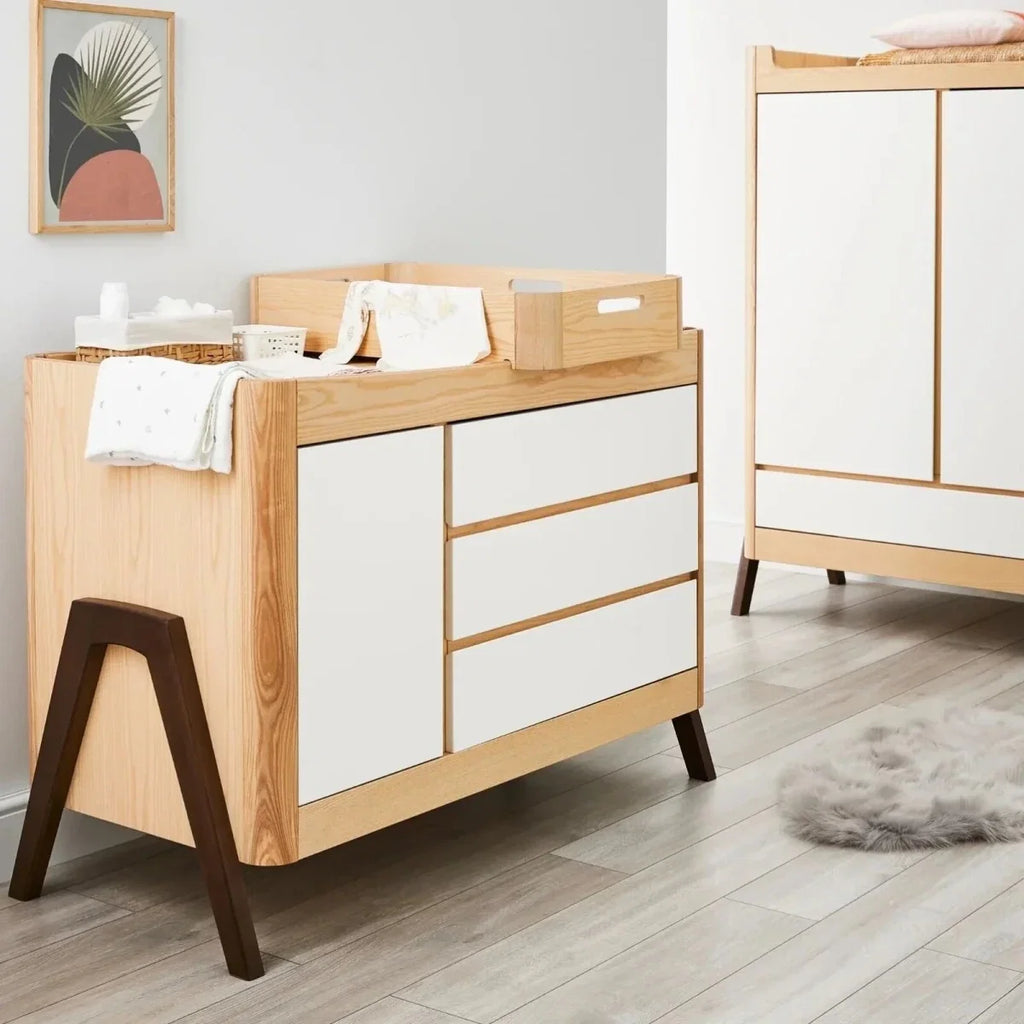 Natural wood baby dresser with white drawers and dark-stained tapered legs