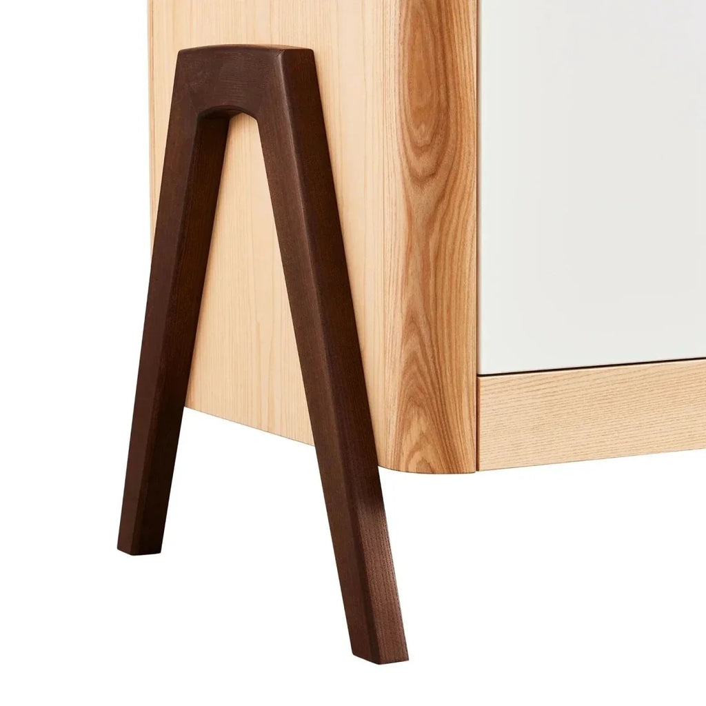Dark-stained A-frame leg of natural wood baby dresser with white drawer panel