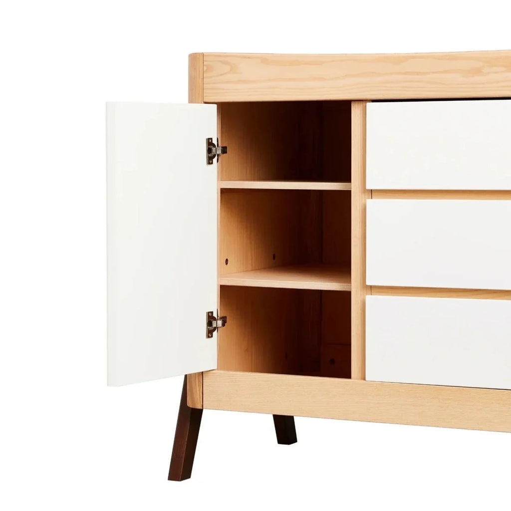 Natural wood baby dresser with side door open to reveal storage shelves
