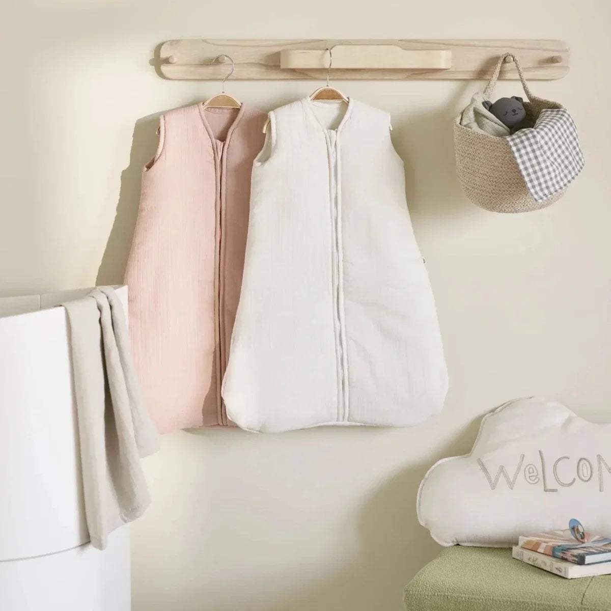Natural wood hanging rail with four pegs, mounted above hanging baby outfits