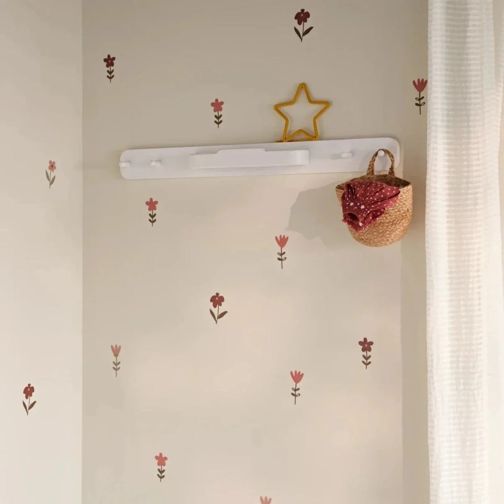White hanging rail mounted on wall with short hooks for baby clothes