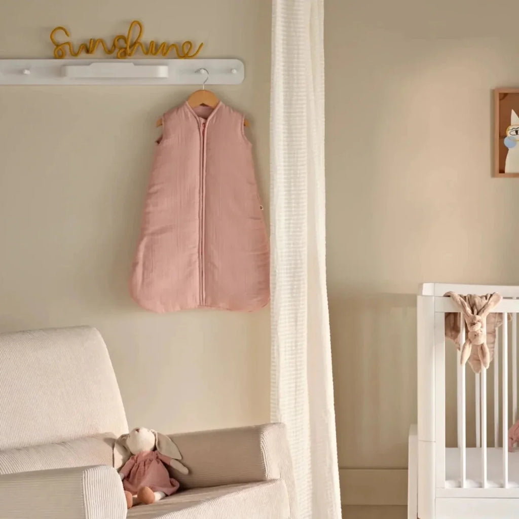 White hanging rail with hangers holding a pink baby sleeping bag
