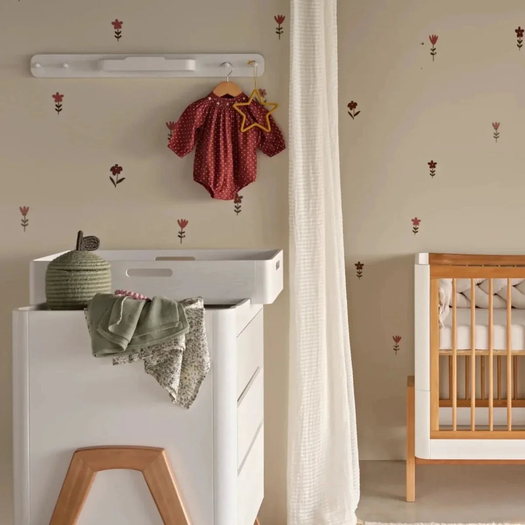 White hanging rail with hangers holding a red baby dress and more clothes