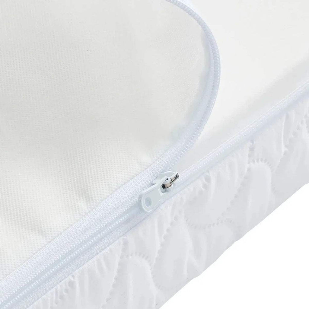 White cot bed mattress with zipped cover and light blue piping along edge.