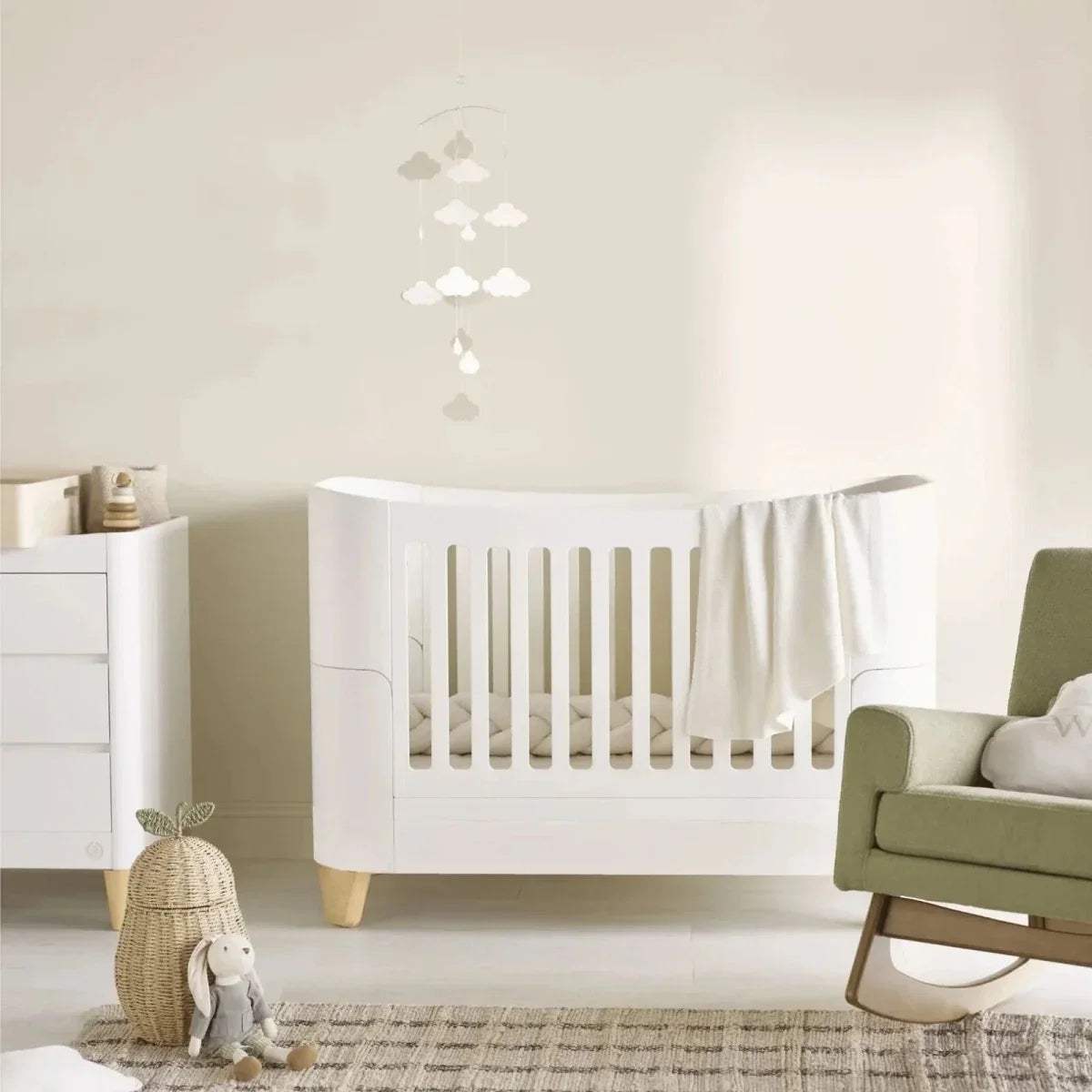 White baby crib with vertical slats and light wood legs