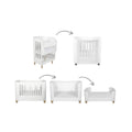 White baby cot bed with vertical slat sides and natural wooden feet