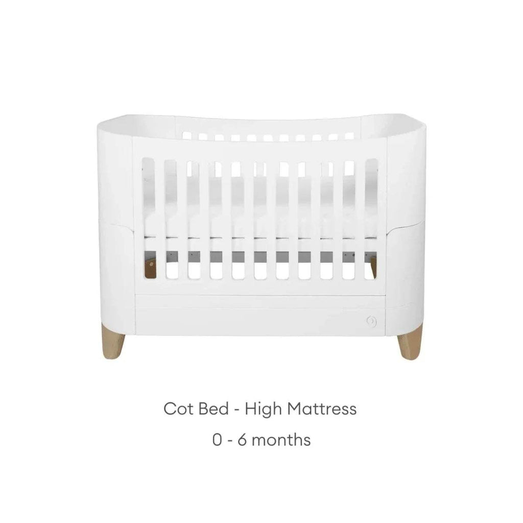 White cot bed with tall slat guard, curved sides, and natural wooden legs