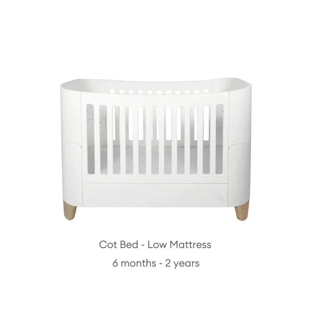 White cot bed with low slat guard and natural wooden legs