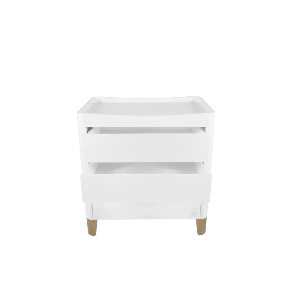 White baby dresser with changing tray and open side shelves, natural wood legs