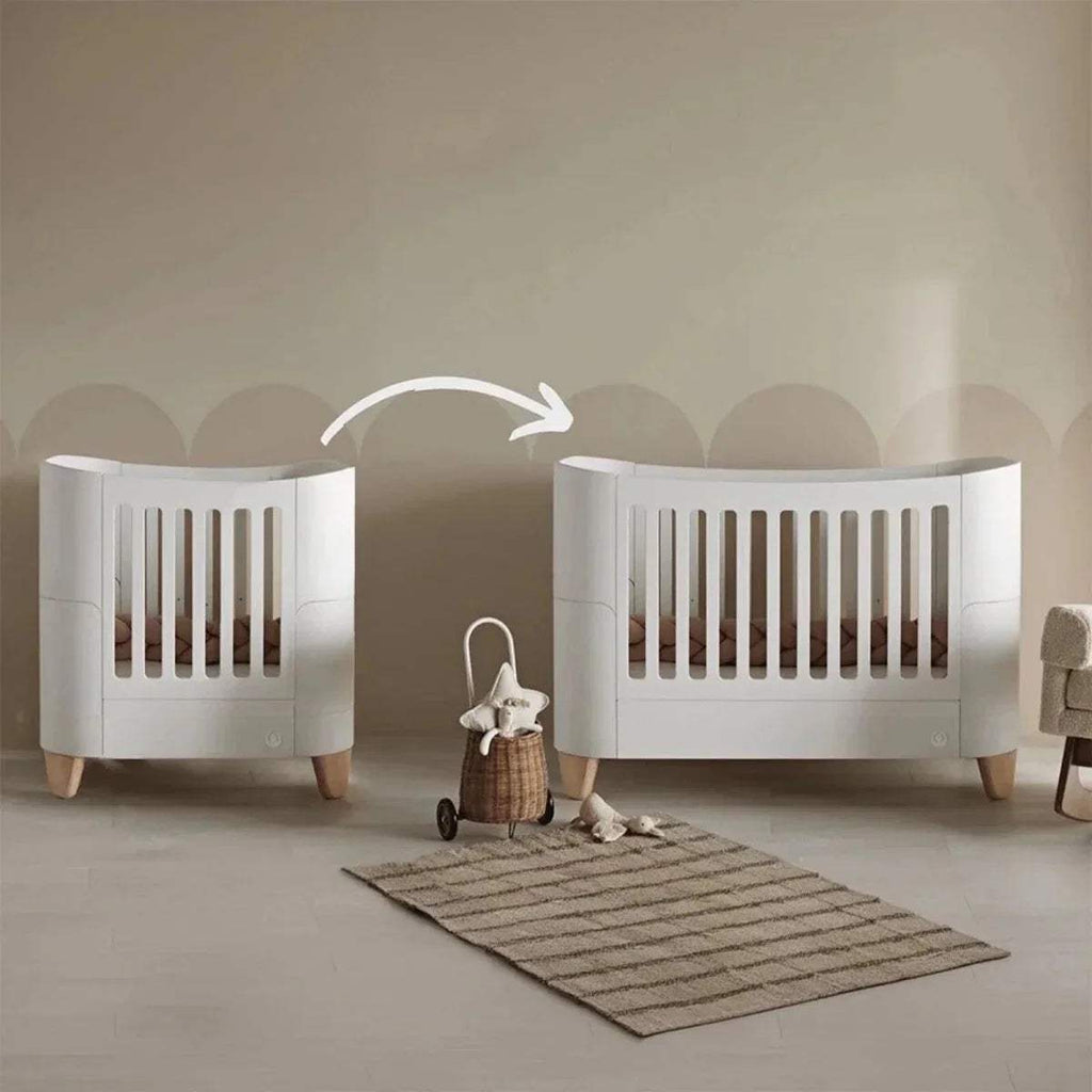 White mini cot bed with vertical slatted sides and rounded end panels