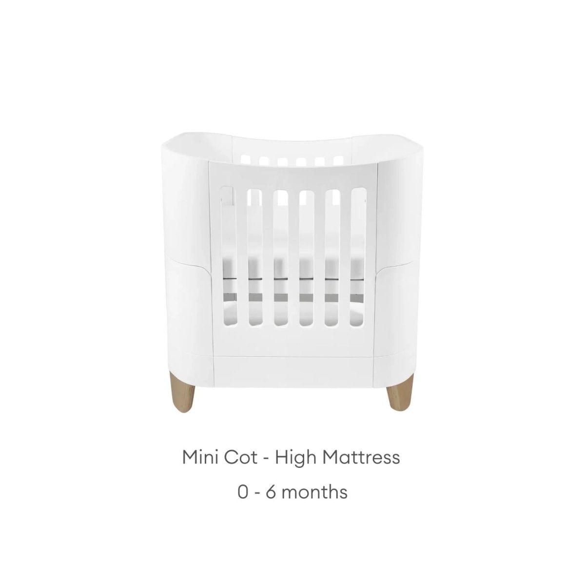 White mini cot with high mattress insert and slatted front, on wooden feet
