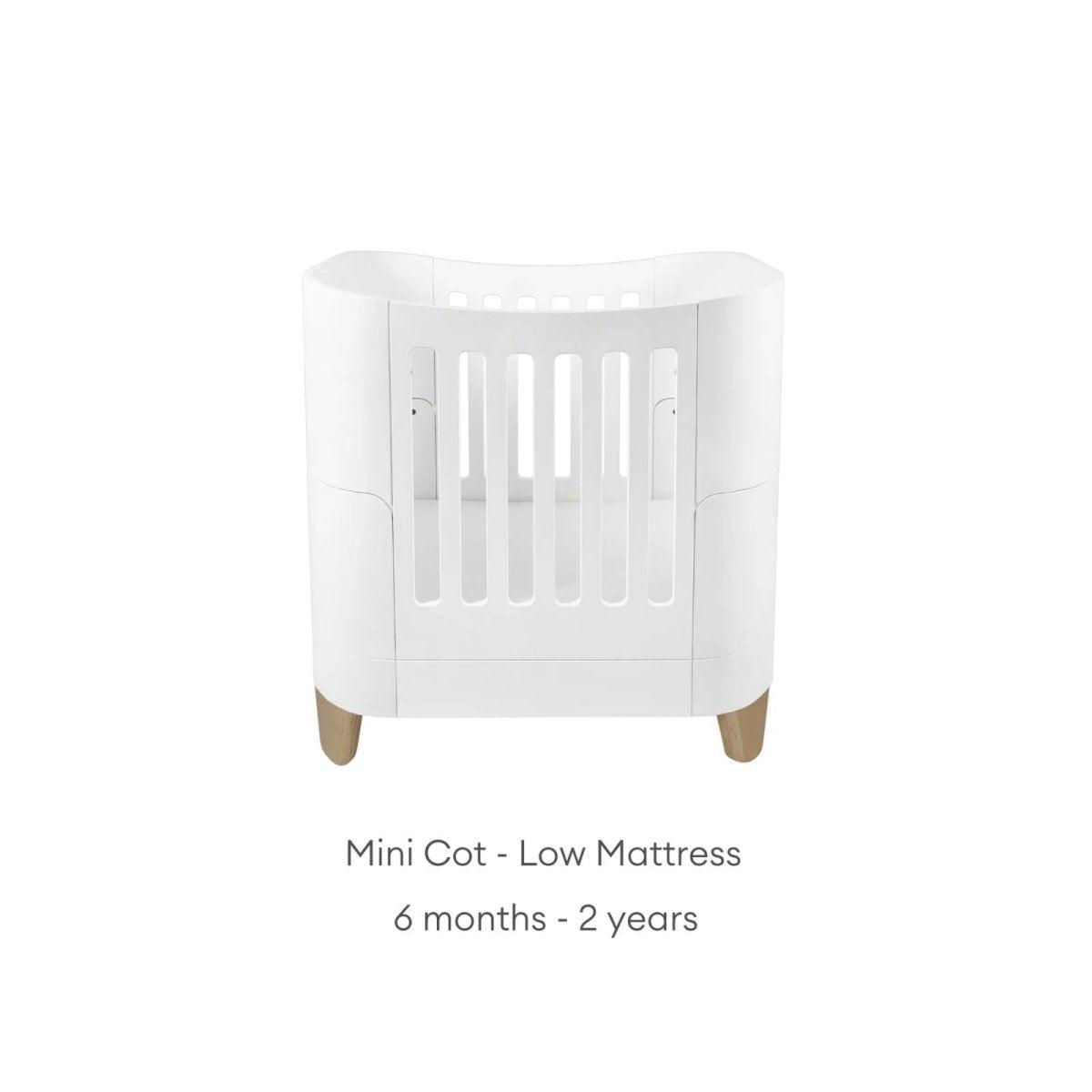 White mini cot with low mattress insert and slatted front, on wooden feet