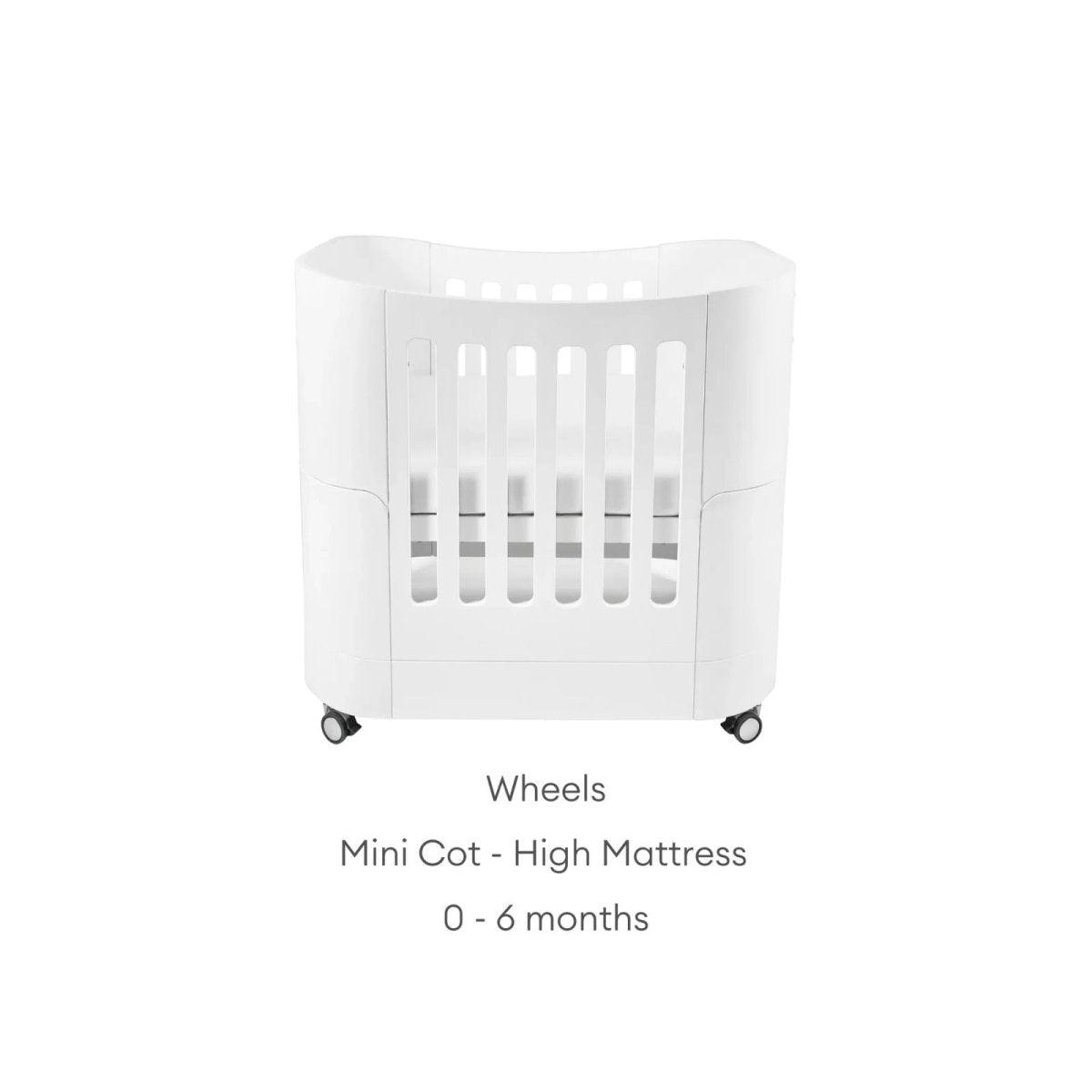 White mini cot on wheels with high mattress insert and slatted front