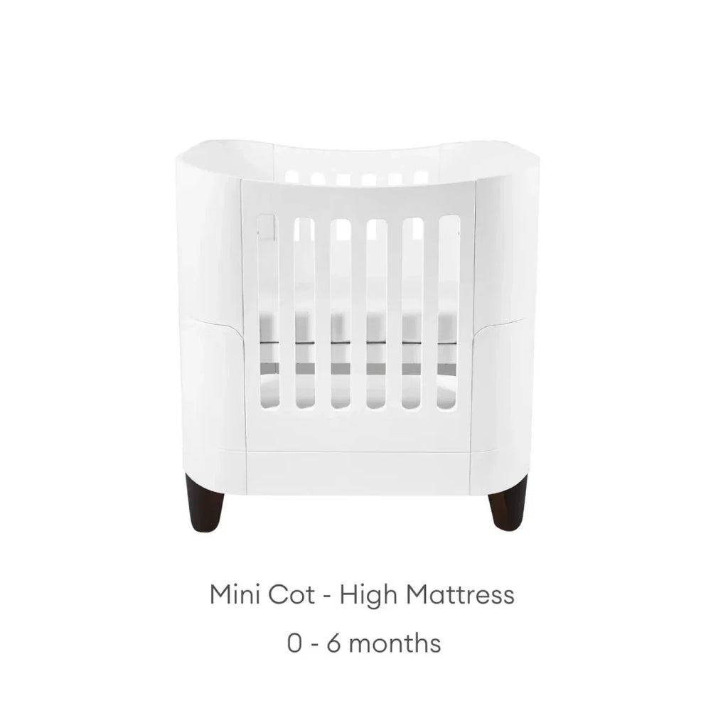 White mini cot with high mattress position, vertical safety rails