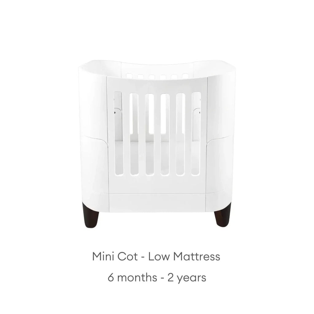 White mini cot with low mattress position, vertical safety rails