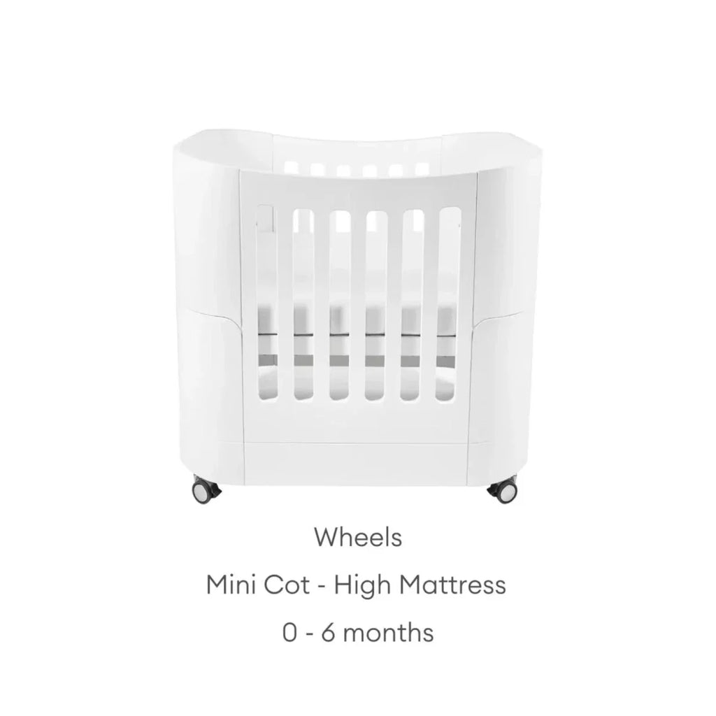 White mini cot on wheels with high mattress position and safety rails