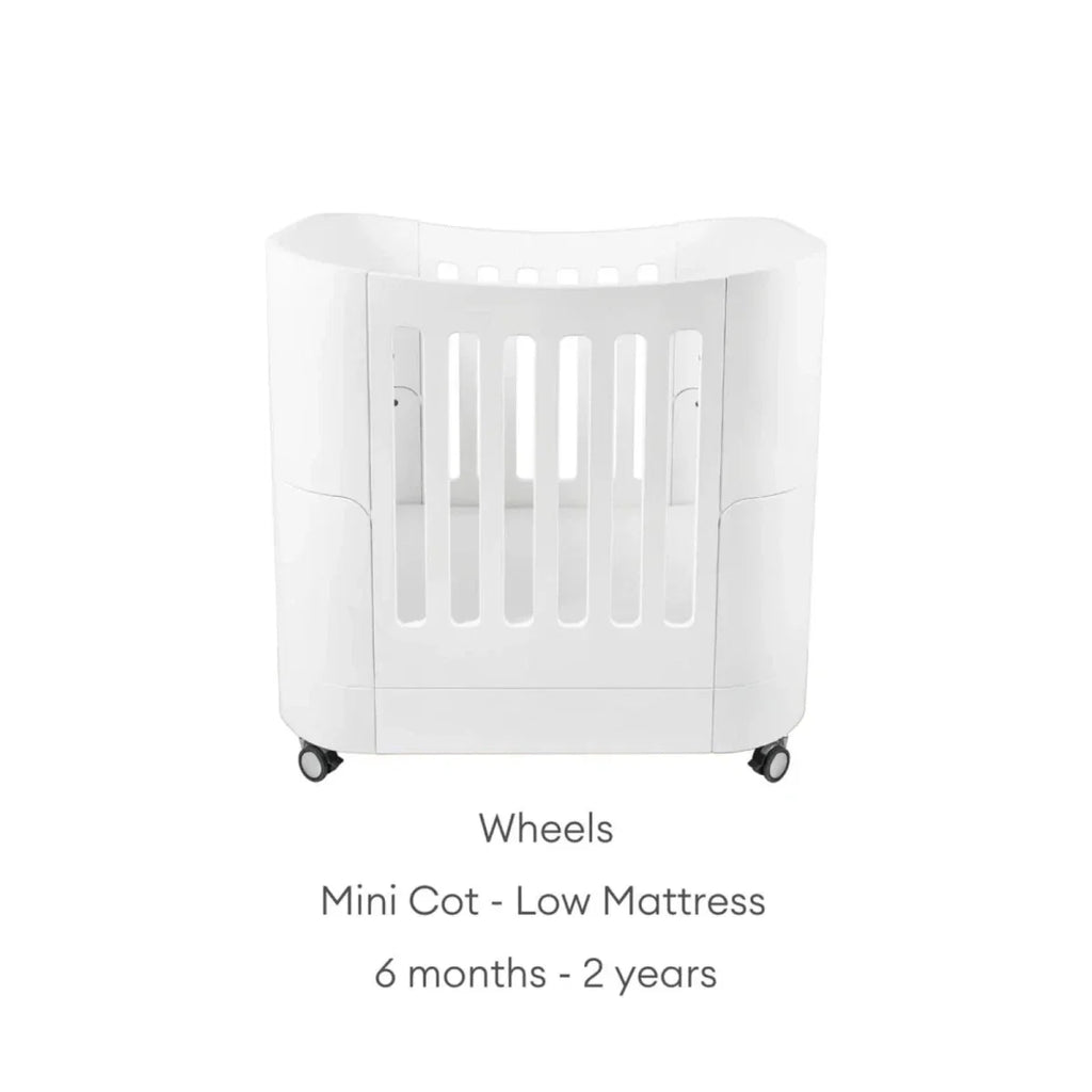 White mini cot on wheels with low mattress position and safety rails