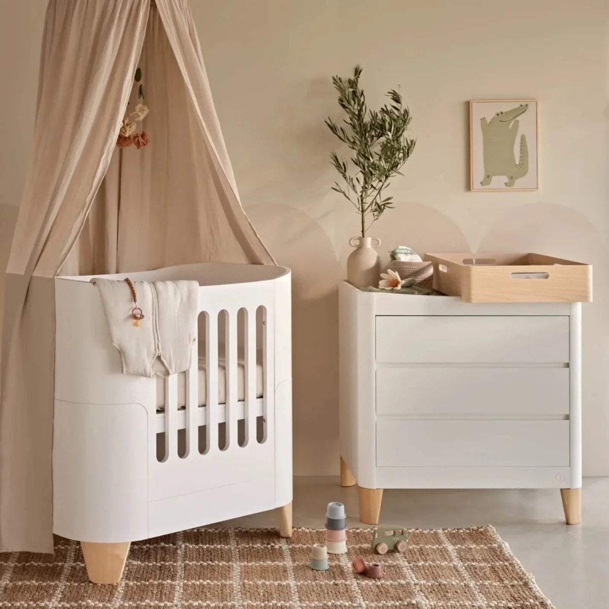 White mini cot bed with slatted side panel and natural wood legs.