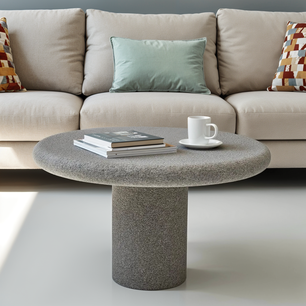 Round stone coffee table in front of a beige sofa with decorative pillows.